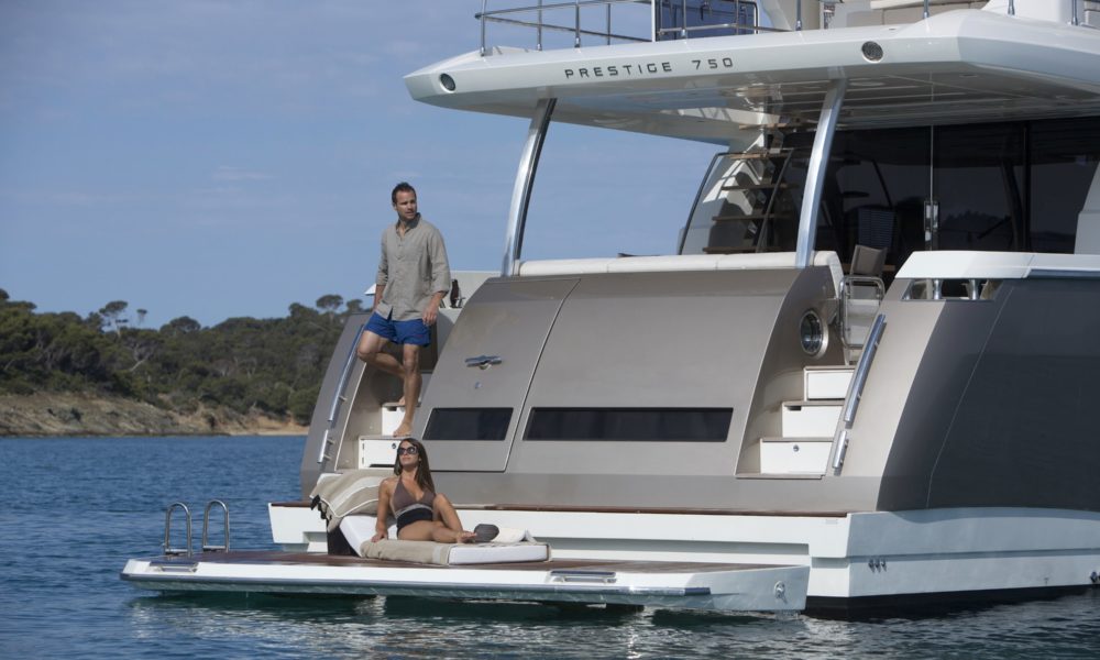 Two people enjoying the hydraulic swim platform on the aft of the Prestige 750