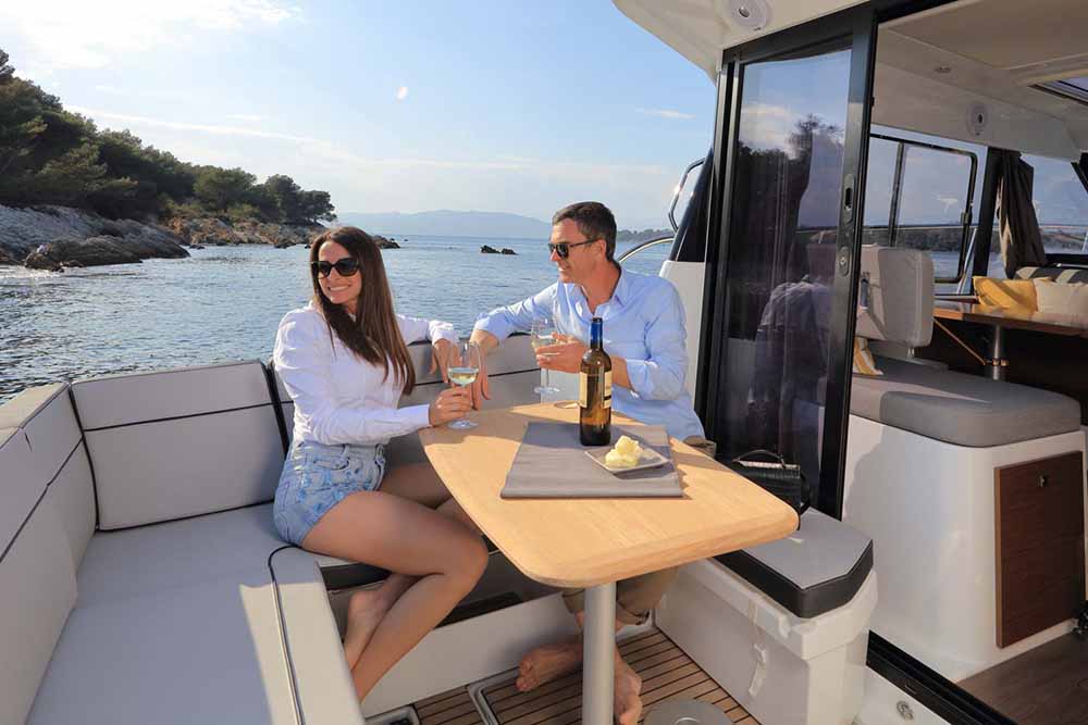 Man and Woman enjoying wine in the cockpit of the Jeanneau 1095