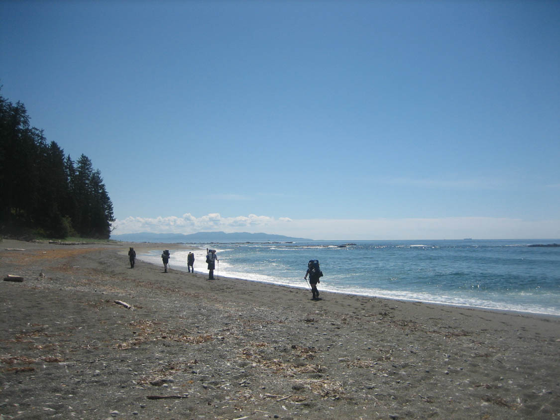 Hikers walking along a beach on a sunny day