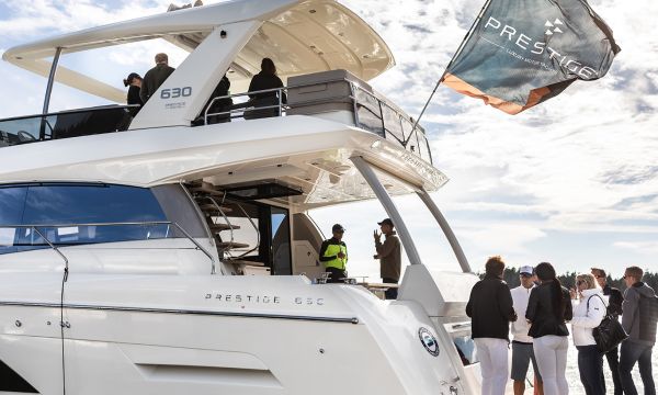 Group of people talking while standing on the swim platform and cockpit of Prestige 630