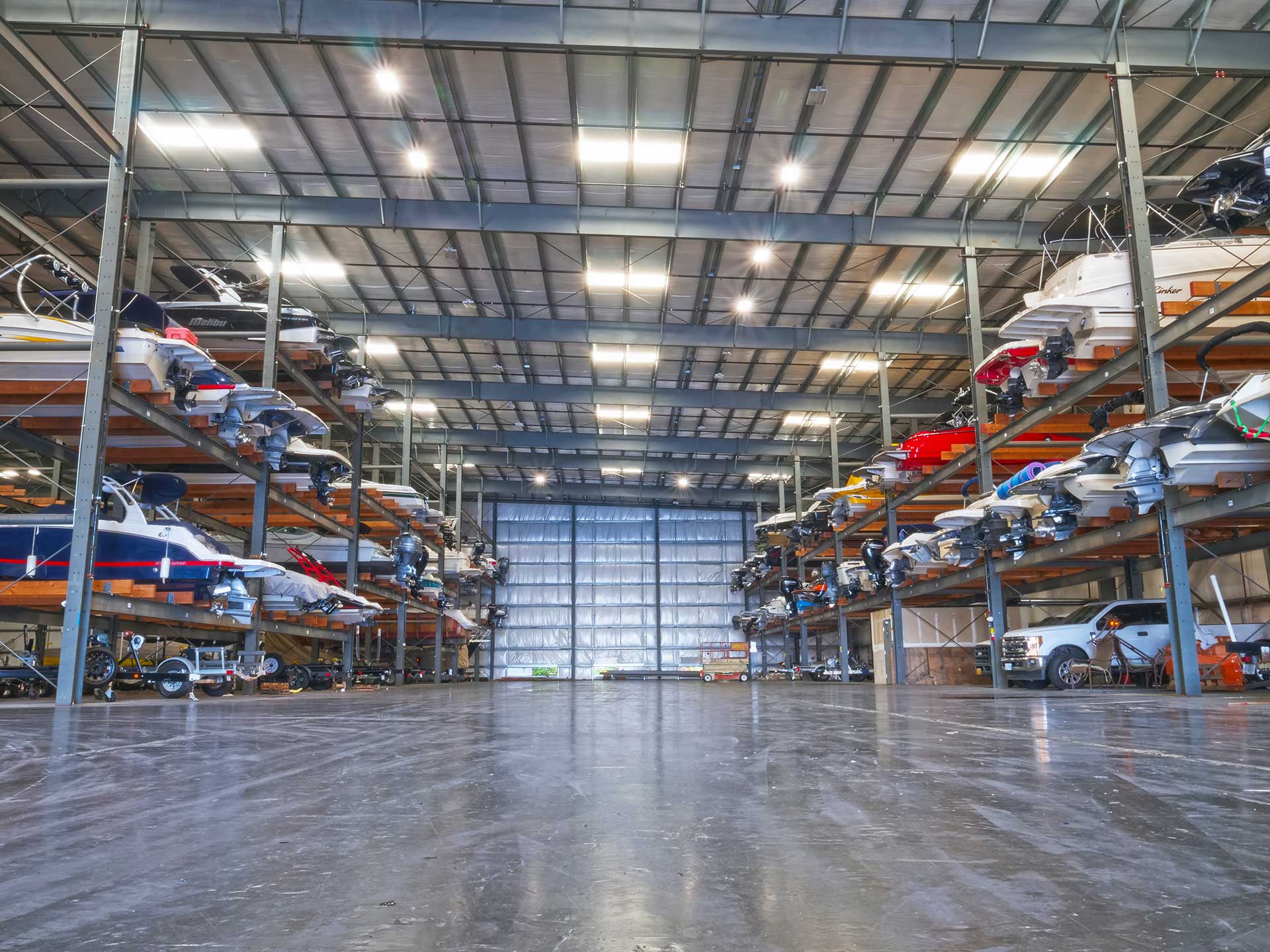 Dozens of boats stored indoor on racks in a heated building