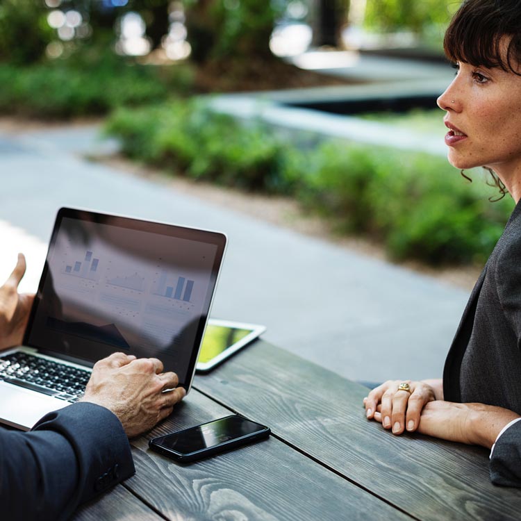 Man and woman looking at a laptop with graphs on screen